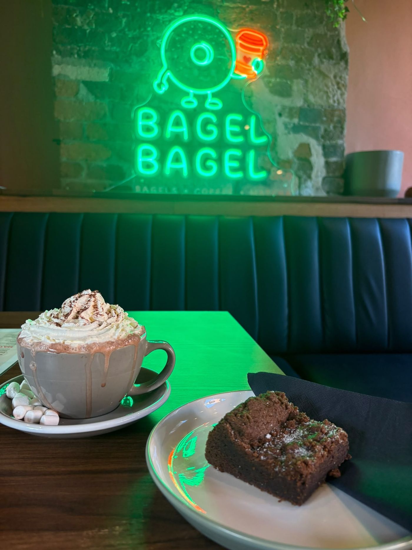 A hot chocolate and a brownie in the Bagel Bagel booth under the green neon sign